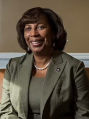 Headshot of G Hagar wear pearl necklace and a green gray suit